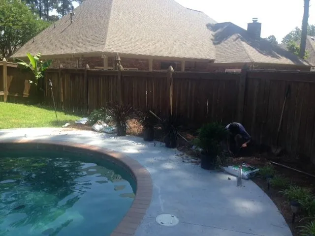 Groundcare Landscape planting shrubs along a wood fence beside a backyard pool