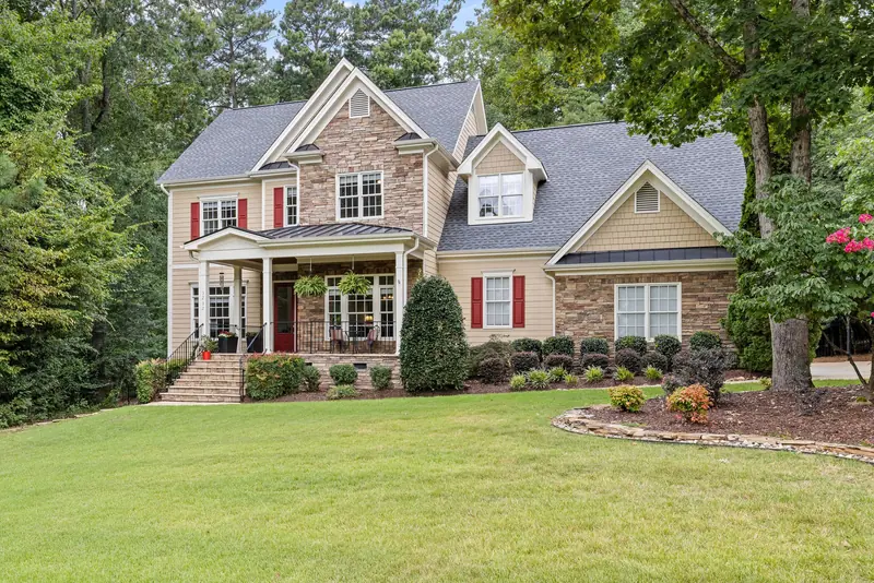 Landscaped home with a stone-edged bed, clipped shrubs and a crape myrtle in bloom