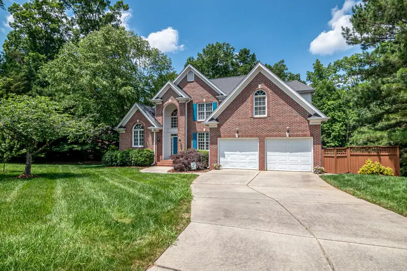 Brick home with fresh mowing stripes in the lawn beside a concrete driveway