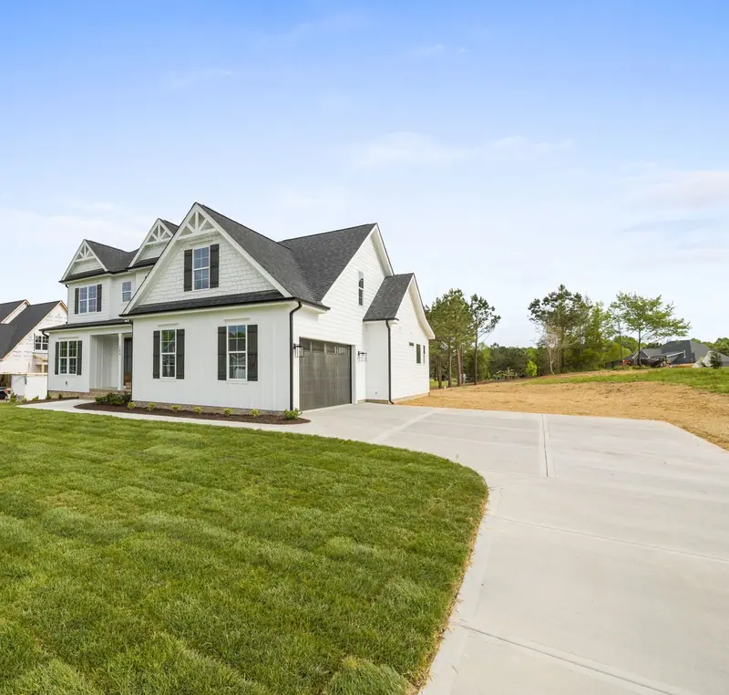 Freshly laid sod with visible seams beside the driveway of a newly built white home