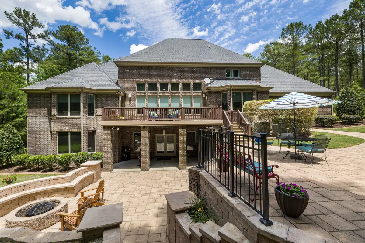 Block retaining walls, a fire pit and a paver patio behind a brick home