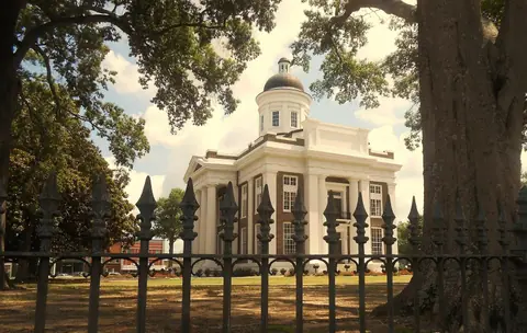 The old Madison County Courthouse on the square in Canton, Mississippi, framed by oak trees
