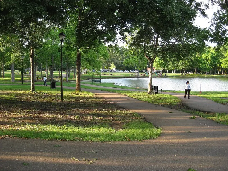 Walking path under shade trees beside the pond at Strawberry Patch Park in Madison, Mississippi
